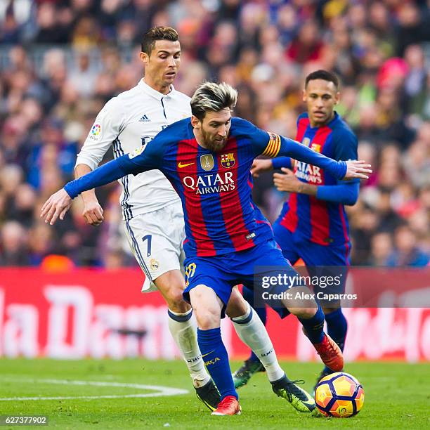 Lionel Messi of FC Barcelona conducts the ball next to Cristiano Ronaldo of Real Madrid CF during the La Liga match between FC Barcelona and Real...