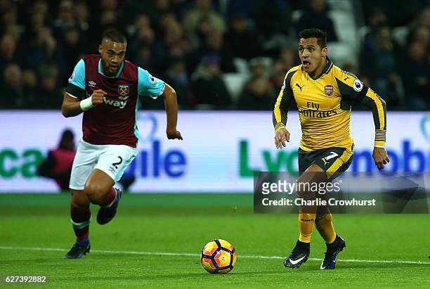 Alexis Sanchez of Arsenal runs with the ball under pressure from Winston Reid of West Ham during the Premier League match between West Ham United and...