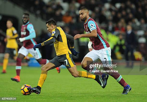 Alexis Sanchez of Arsenal takes on Winston Reid of West Ham during the Premier League match between West Ham United and Arsenal at London Stadium on...