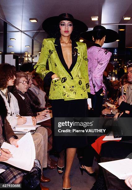 Fashion model wears a v-neck haute couture blazer and skirt with a wide brimmed hat by French fashion designer Jean-Louis Scherrer. She modeled the...