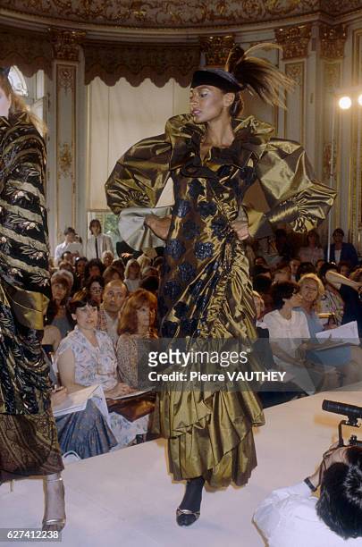 Fashion model wears an olive green haute couture evening gown with ruffles and puffed sleeves by French fashion designer Marc Bohan for French...