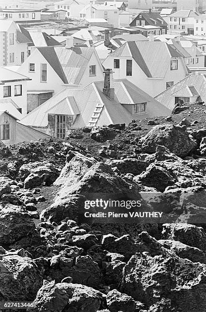 Rooftops of houses in Heimaey, in Rangarvallasyla, surrounded by hills of volcanic ash.