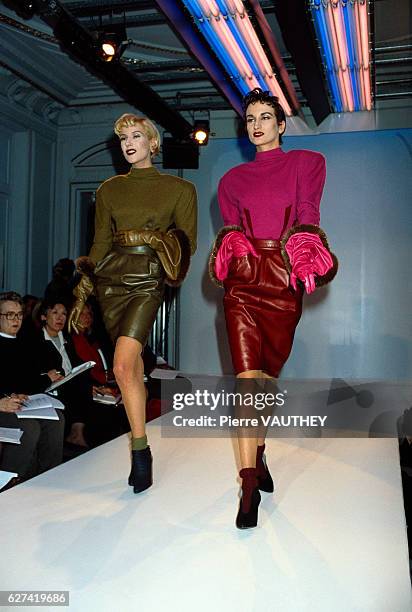 Two fashion models wear sweaters and matching leather skirts by German fashion designer Thierry Mugler at his autumn-winter 1987-1988 fashion show in...