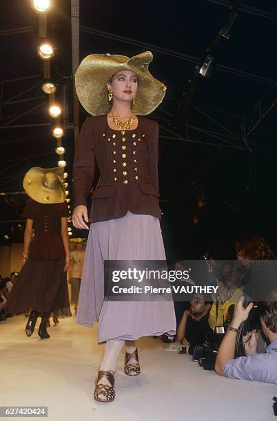 Fashion model wearing a ready-to-wear blazer and skirt with a wide-brimmed hat by French fashion designer Lolita Lempicka. She is modeling the outfit...