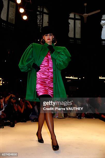 Fashion model wears a green coat over a magenta cocktail dress by French fashion designer Emanuel Ungaro at his autumn-winter 1986-1987 fashion show...
