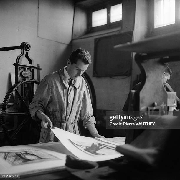 French painter Bernard Buffet creates a print in his studio. Buffet's figurative paintings were associated with the philosophical movement known as...