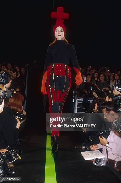 Fashion model wears a ready-to-wear outfit decorated with zippers with a headdress adorned with a cross motif by French fashion designer Jean Paul...