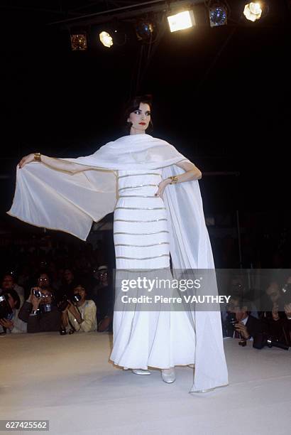 Fashion model wears a white haute couture evening gown with a wrap by German fashion designer Karl Lagerfeld for French fashion house Chanel. She...