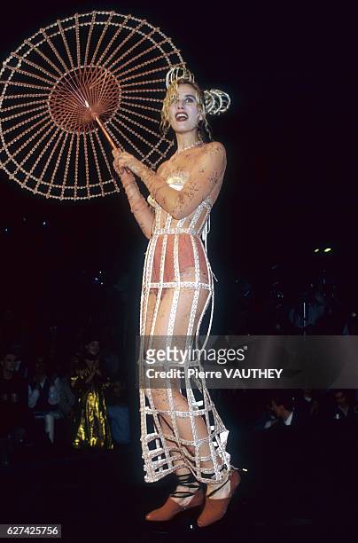Fashion model wears a ready-to-wear outfit with a beaded parasol by French fashion designer Jean Paul Gaultier. She is modeling the outfit during his...