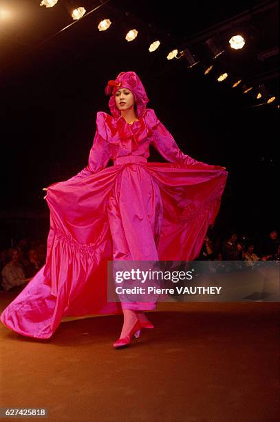 Japanese design house Kenzo shows its 1984-1985 fall-winter women's ready-to-wear line in Paris. The model is wearing a bright fuchsia dress with a...