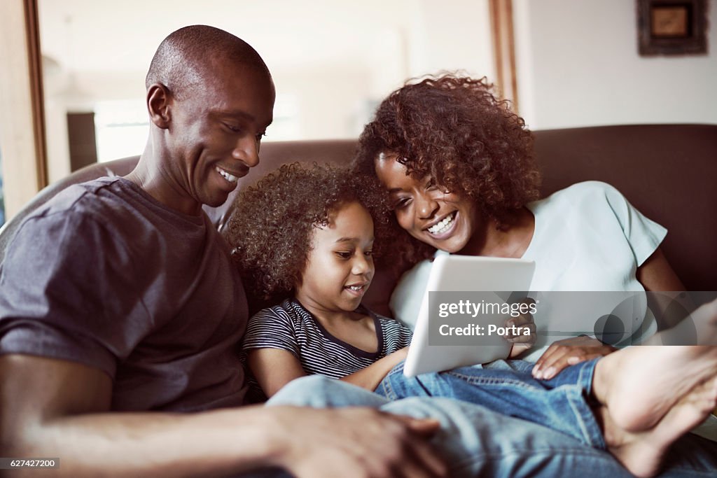 Glückliche Eltern, die Sohn mit digitalem Tablet anschauen