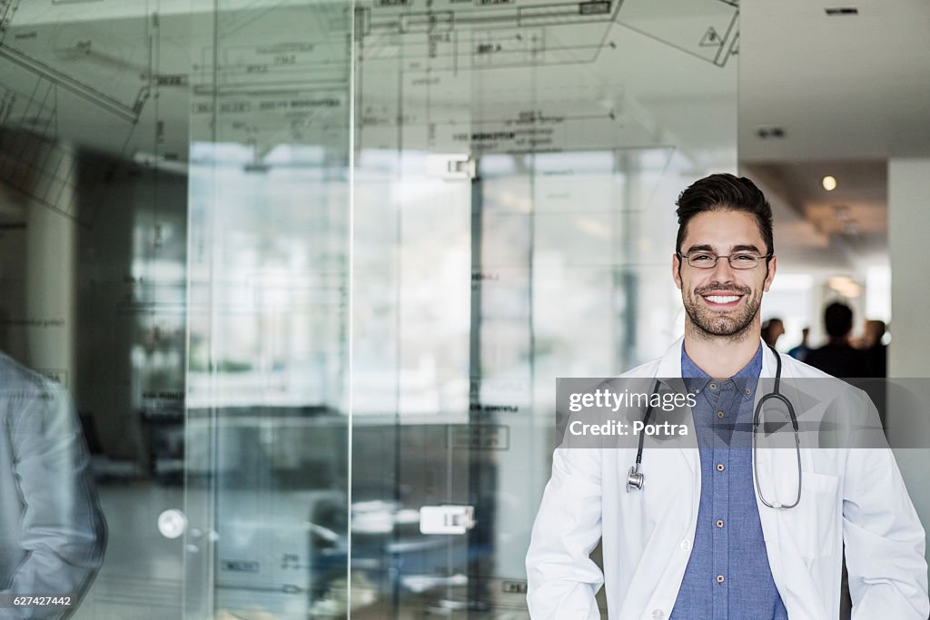Porträt eines glücklichen männlichen Arztes, der in der Klinik steht