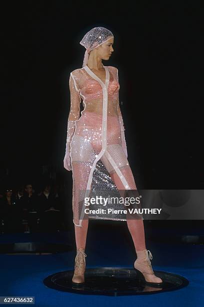 Fashion model wears a sheer ready-to-wear jacket over pink lingerie by French fashion designer Jean Paul Gaultier. She modeled the outfit during his...