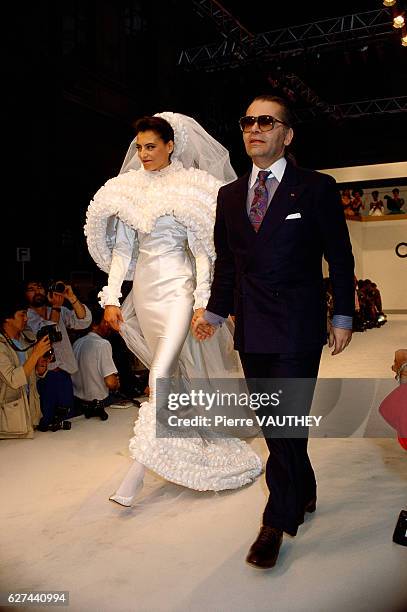 French fashion model Ines de la Fressange walks with German fashion designer Karl Lagerfeld in his haute couture wedding dress for French fashion...