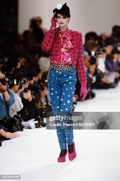 Supermodel Kristen McMenamy wears a ready-to-wear magenta blazer and blouse with jeans decorated with gold coins by German fashion designer Karl...