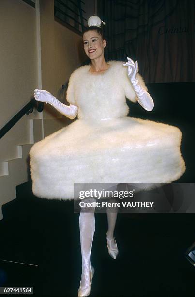 Fashion model wears a ready-to-wear fuzzy white cocktail dress with wide skirt by French fashion designer Chantal Thomass. She is modeling the dress...