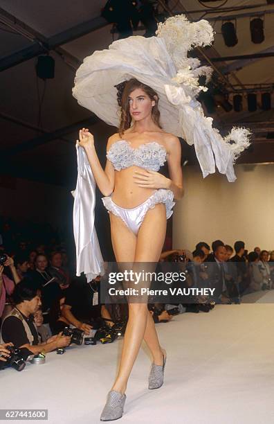 Fashion model wears a women's ready-to-wear strapless brassiere and panties with an ornate brimmed hat by French fashion designer John Galliano at...