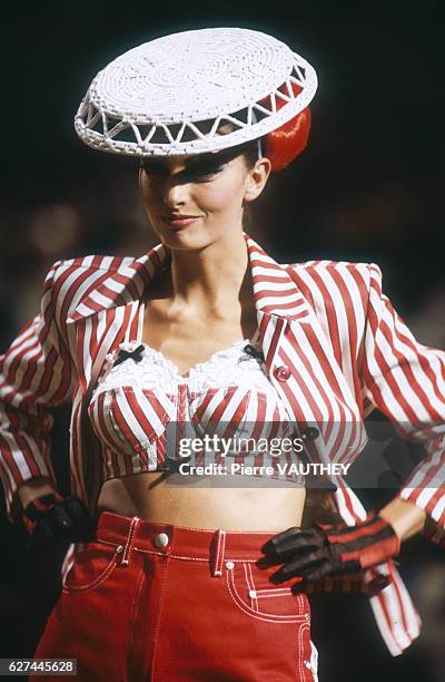 Fashion model wears a women's ready-to-wear red striped suit with bustier and a brimmed hat by French fashion designer Jean-Paul Gaultier at his...