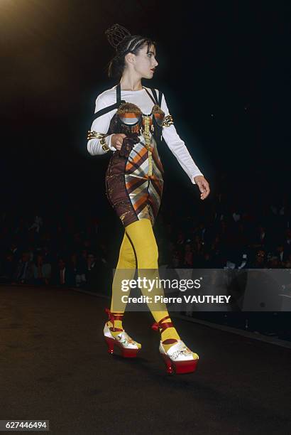 Fashion model wears a ready-to-wear corset with a shirt and stockings by French fashion designer Jean Paul Gaultier. She is modeling the outfit...