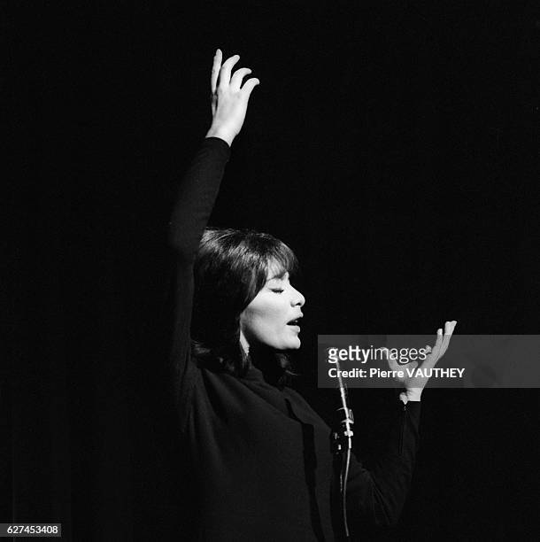 French singer Juliette Greco raises her arms during her performance at the Olympia Concert Hall in Paris.