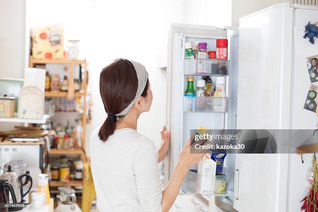 The back of a woman who opens a refrigerator