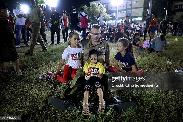 Family looks at a mobile phone as tens of thousands of people gather in Revolution Plaza for a memorial event for former Cuban President Fidel Castro...