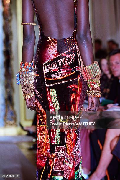 Fashion model wearing bracelets and a woman's haute couture multicolored evening dress with Gaultier Paris on it designed by French fashion designer...