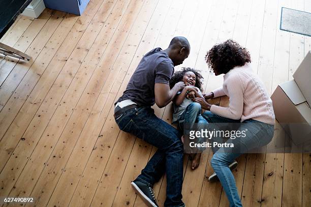 cheerful parents playing with son on at new home - kid lying down stock pictures, royalty-free photos & images