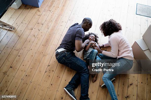 cheerful parents playing with son on at new home - moving to lying down position stock pictures, royalty-free photos & images