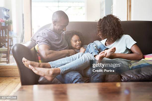 cheerful family sitting on sofa at home - brightly lit living room stock pictures, royalty-free photos & images