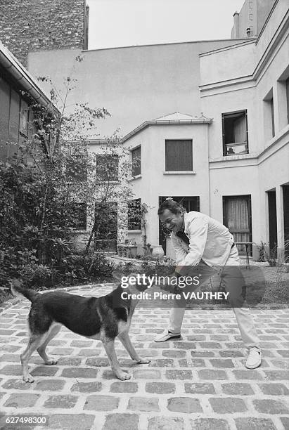 Singer and actor Serge Reggiani plays with his dog outside his Paris home.