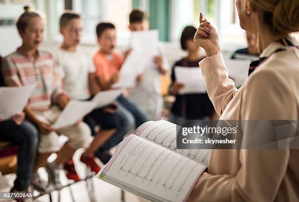 unkenntlich, dass der lehrer während des musikunterrichts eine lektion erteilt. - gesangsunterricht stock-fotos und bilder