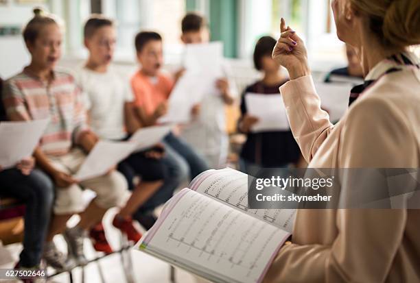 unkenntlich, dass der lehrer während des musikunterrichts eine lektion erteilt. - child singing stock-fotos und bilder