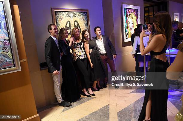 Guests pose for a photo at the Underwater Dreams To Life In Color - Art Exhibit Featuring Antonio Dominguez De Haro And Romero Britto At Four Seasons...