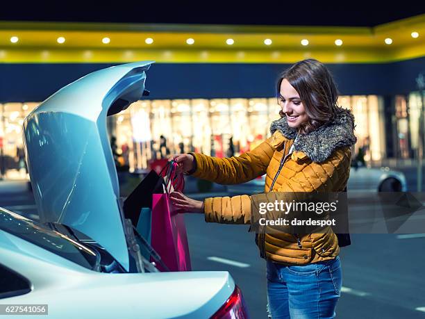 mulher colocando sacos de compras no carro - shopping bag imagens e fotografias de stock