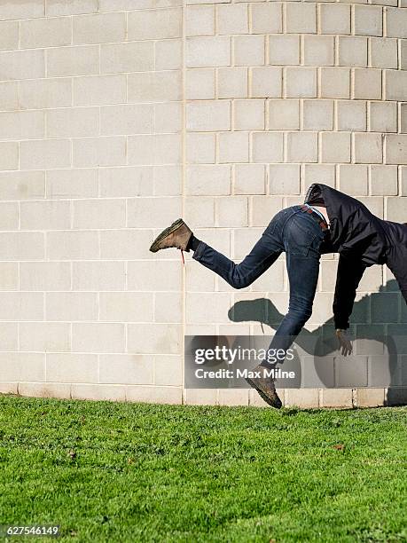 caucasian man falling near brick wall - stumble stock pictures, royalty-free photos & images