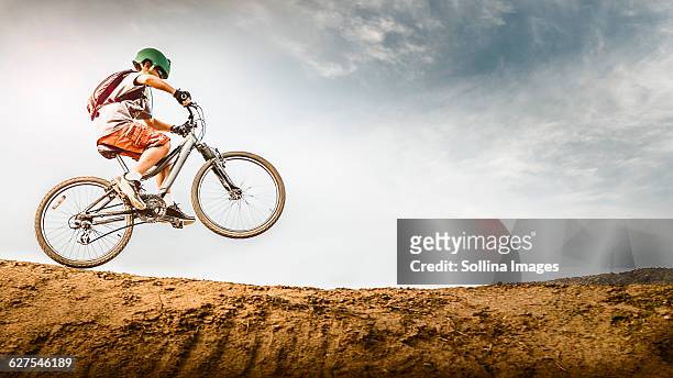 mixed race boy riding dirt bike on track - wheelie stock-fotos und bilder