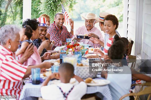multi-generation black family eating at fourth of july barbecue - black family reunion stock pictures, royalty-free photos & images