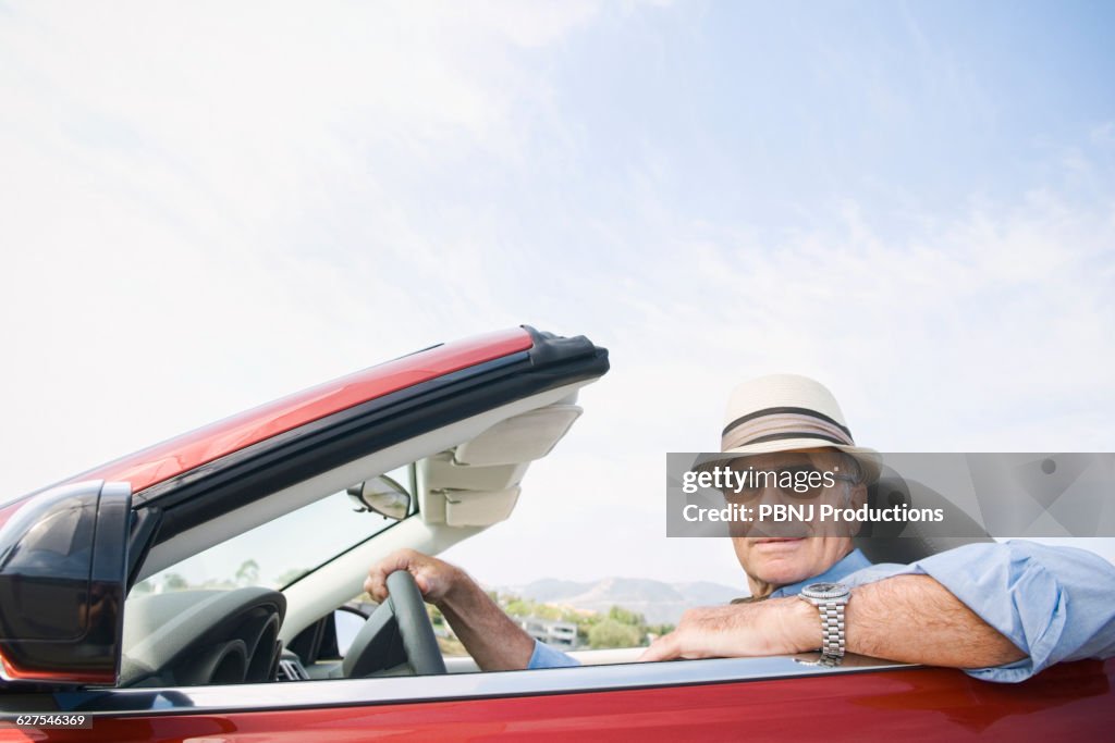 Older Caucasian man driving convertible