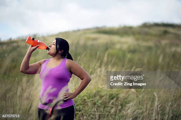 female jogger drinking water from bottle - arabische muster stockfoto's en -beelden