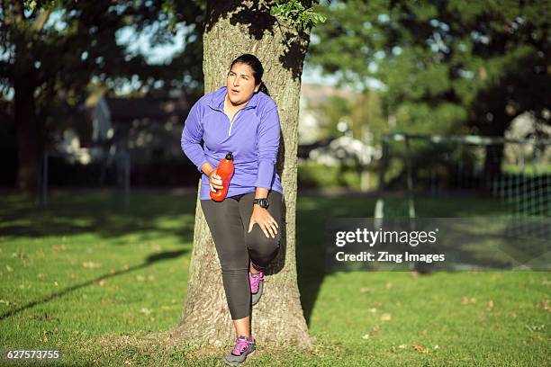 female jogger leaning against tree - chubby arab 個照片及圖片檔