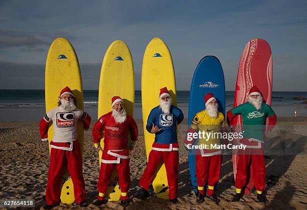 Surfers dressed as Santa pose for a photograph before competing in a heat during the annual Surfing Santa as part of the Santa Run and Surf 2016 at...