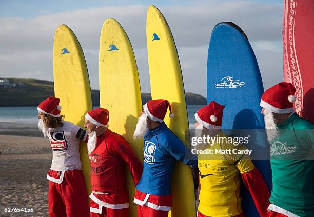 Surfers dressed as Santa pose for a photograph before competing in a heat during the annual Surfing Santa as part of the Santa Run and Surf 2016 at...