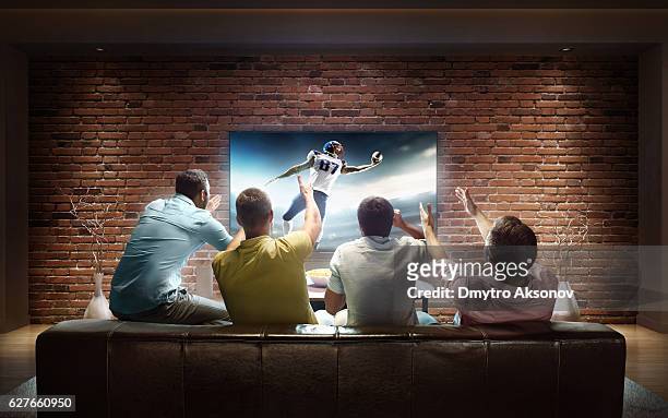 students watching american football game at home - football stock pictures, royalty-free photos & images