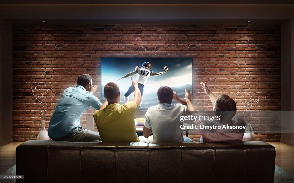 Estudantes assistindo jogo de futebol americano em casa