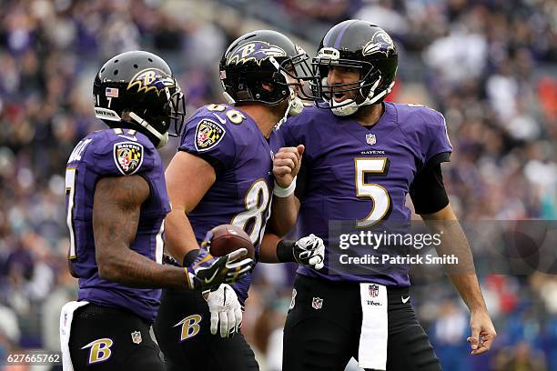 Tight end Dennis Pitta of the Baltimore Ravens celebrates with teammates wide receiver Mike Wallace and quarterback Joe Flacco after scoring a first...