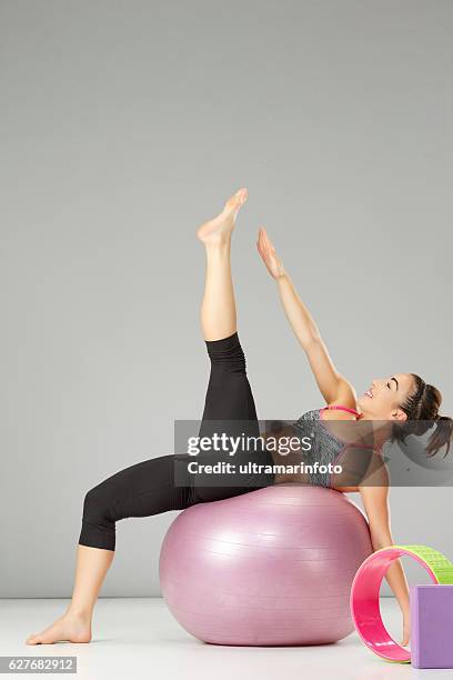 entrenamiento de estiramiento de pilates mujer practicando en una pelota de fitness - training wheels fotografías e imágenes de stock