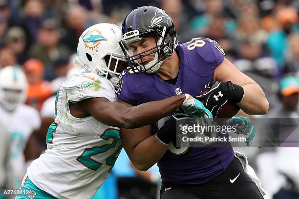 Tight end Dennis Pitta of the Baltimore Ravens is tackled by strong safety Isa Abdul-Quddus of the Miami Dolphins in the first quarter at M&T Bank...