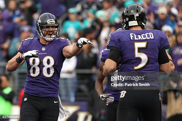 Tight end Dennis Pitta of the Baltimore Ravens celebrates with teammate quarterback Joe Flacco after scoring a second quarter touchdown against the...