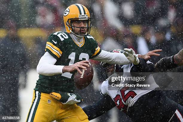 Aaron Rodgers of the Green Bay Packers is pressured by Christian Covington of the Houston Texans during the first half of a game at Lambeau Field on...